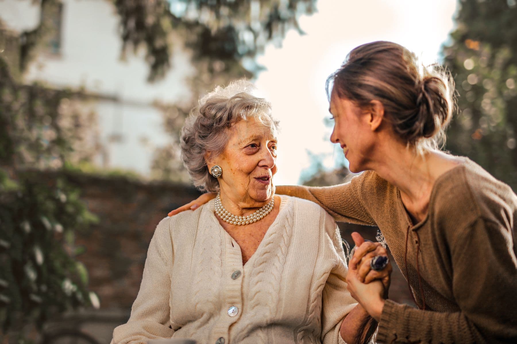 An adult daughter laughing with her mother in a garden